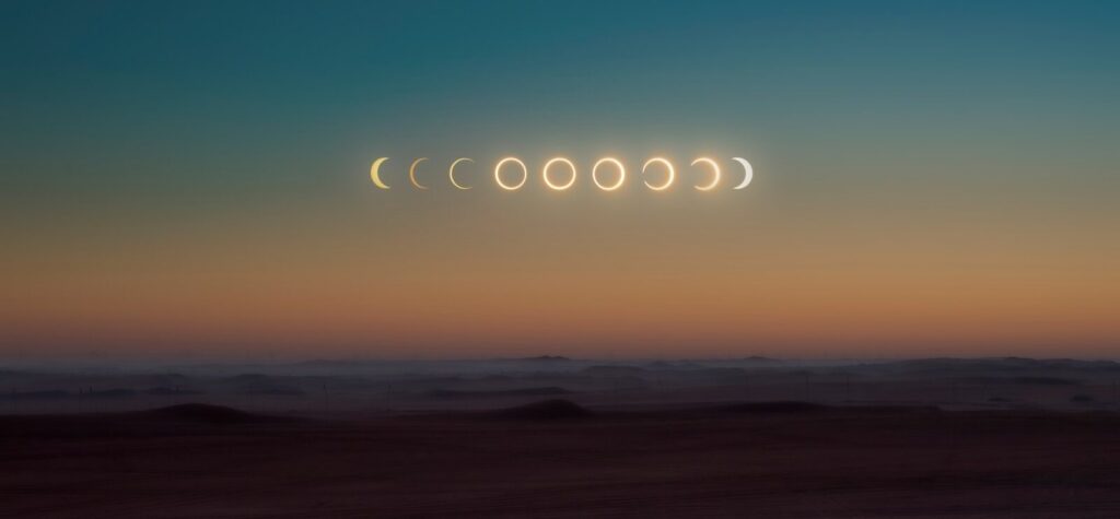 A sequence of solar eclipse phases above a dark desert landscape at twilight