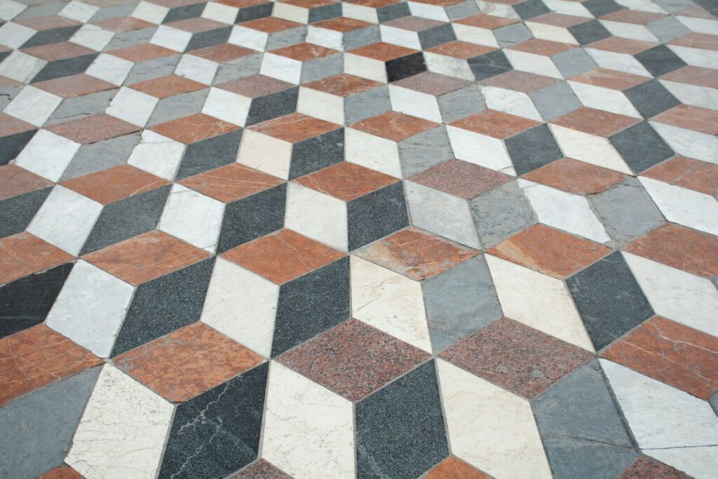 A marble floor with a geometric pattern of red, white, and grey cubes